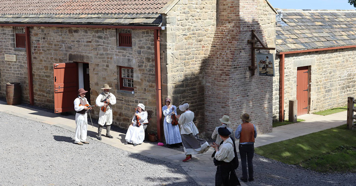 group of people dressed in Georgian costumes standing and taking outside the Drovers Tavern at Beamish Museum.